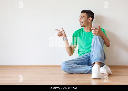 Special mobile offer. Excited man pointing aside at free space holding cellphone over light wall background Stock Photo