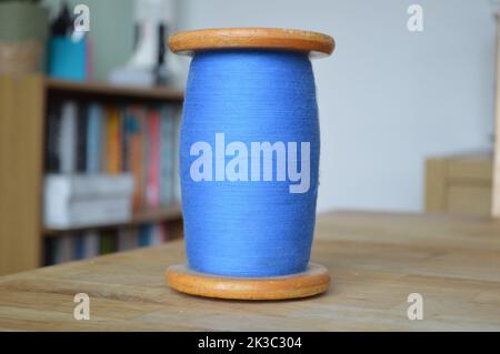 Large Blue Cotton Bobbin on a Wooden Table Stock Photo