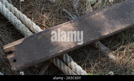 Wooden board and thick rope rope on dry grass Stock Photo