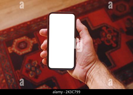 Mockup of of smartphone blank white touchscreen in male hand, man using mobile phone at home, selective focus Stock Photo