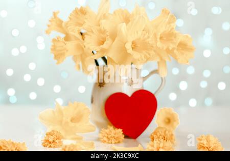 Spring postcard. Bouquet of yellow daffodils in a jug on table against the background of glowing lights. Spring composition Stock Photo