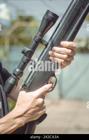 Snipe rifle in the hands of a Ukrainian man. A man is holding a large sniper rifle, close-up. Air rifle with optical sight Stock Photo