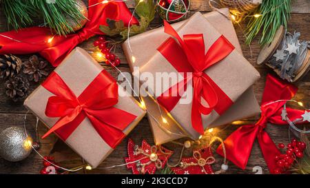 Gift boxes with red ribbons and Christmas tree toys on a wooden background. Stock Photo