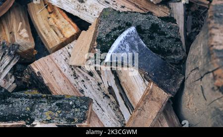 An old axe with a wooden handle lies on a stack of firewood, top view close up Stock Photo