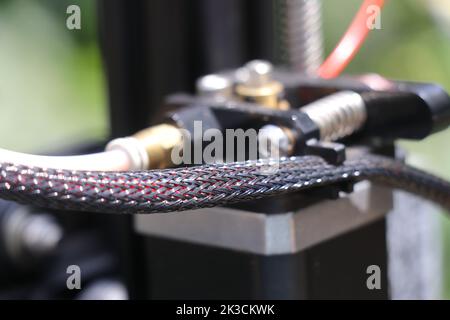 Wires of an extruder close up with a view of filament feeding mechanism using a stepper motor on background Stock Photo