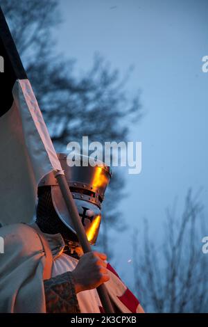 Interpretation of a Templar Knight standing in the cold night by a fire holding the bauceant war flag or banner. Stock Photo