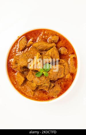 Beef masala or roast,kerala style homemade recipe garnished with coconut pieces and curry leaves which is arranged in white bowl with white background Stock Photo