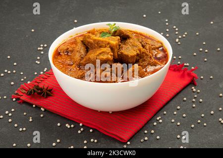 Beef masala or roast,kerala style homemade recipe garnished with coconut pieces and curry leaves which is arranged in white bowl with white background Stock Photo