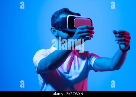 Young bearded man using virtual reality headset. VR, future, gadgets, technology, education online, studying, video game concept, metaverse. Stock Photo