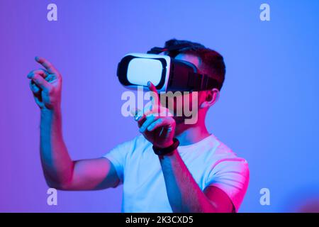 Young bearded man playing virtual reality game using VR goggles. Stock Photo