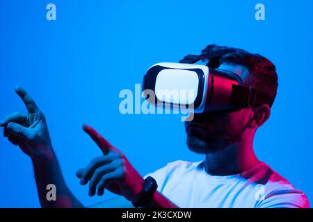 Man's portrait of bearded man wearing virtual reality glasses. Handsome caucasian male using VR headset, playing video games. Playing with VR. Stock Photo