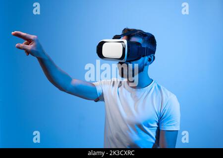 Young bearded man wearing virtual reality glasses and playing video games. Stock Photo