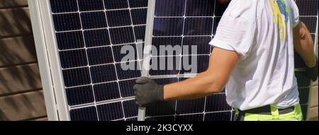 Close-up of man worker carrying solar panel for installing. Stock Photo