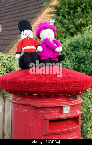 Quirky colourful handmade knitted woollen hat decorates a traditional red pillar box, celebrating the platinum Jubilee of Queen Elizabeth II. 2022, UK. Stock Photo