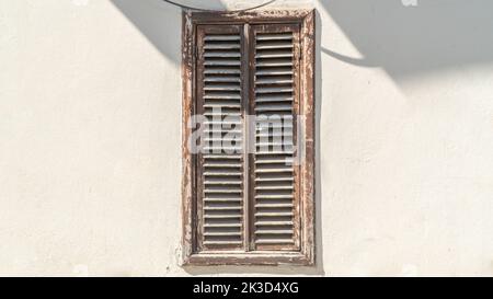 Closed wooden window shutters on a white wall, background Stock Photo