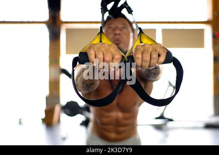 Horizontal photo with selective focus on the hands of a man exercising with trx Stock Photo