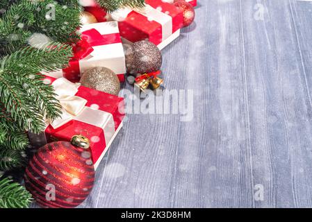 Present Boxes With Christmas tree on wooden background. Various red and white gifts with festive ribbon, fir tree branches and Xmas decoration on old Stock Photo
