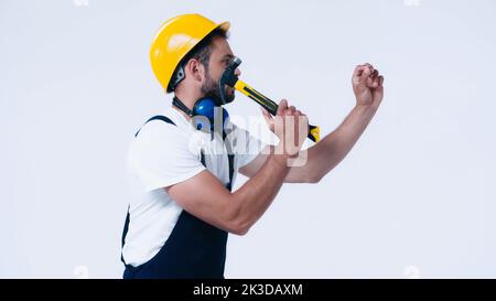 side view of handyman in hardhat working with hammer isolated on white,stock image Stock Photo