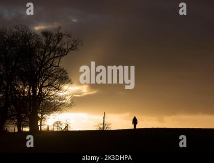 Person in silhouette, walking towards bright light at the end of a dark ...