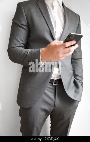 Midsection of businessman holding a mobile phone for communicating Stock Photo