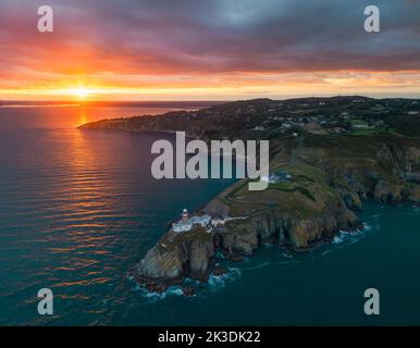 The sun setting in the west from an aerial view of the Baily Lighthouse taken off from Howth Summit Stock Photo