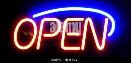 Open sign neon on glass window or door for business at night glowing with color Stock Photo