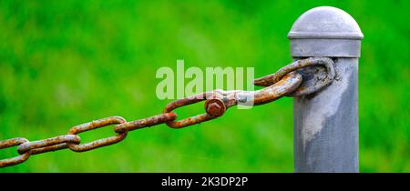 Detail of chain connected to pole for security and protection green background Stock Photo