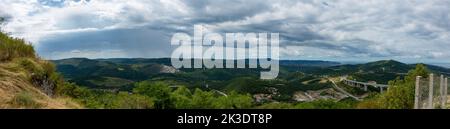 A panoramic view of green mountains of Crni Kal village under a cloudy sky in Slovenia Stock Photo