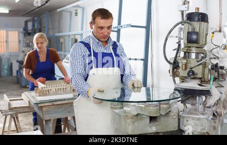 Man working on curved glass beveling machine Stock Photo