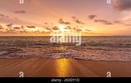 Beautiful sunset above sea or ocean. Vibrant and soft colors, magic light. Small clouds on the sky, reflection of sun in the water and sand on beach. Stock Photo
