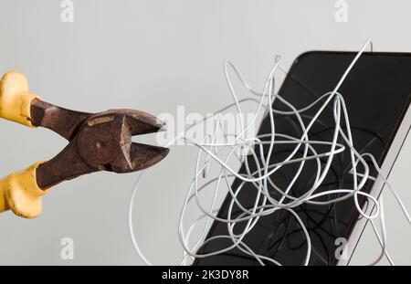 coiled metal wire cutting pliers, smartphone greenish gray background, censorship of social networks. cancel cultural ban, erase Stock Photo