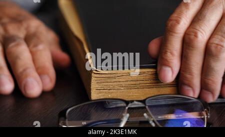 A man's hand and an old book on the table Stock Photo