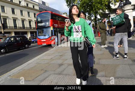 London, England, UK. Young Asian woman with a mobile phone in the Strand Stock Photo