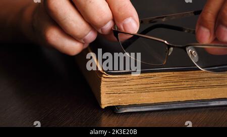 A man's hand and an old book on the table Stock Photo