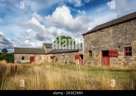 Beautiful old barns with matching red woodwork on the windows and barn doors, North Yorkshire, England, UK Stock Photo
