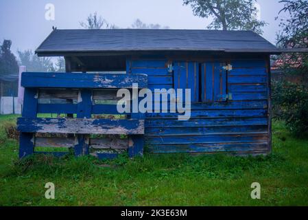 Old playhouse with chipped paint in a backyard in autumn Stock Photo