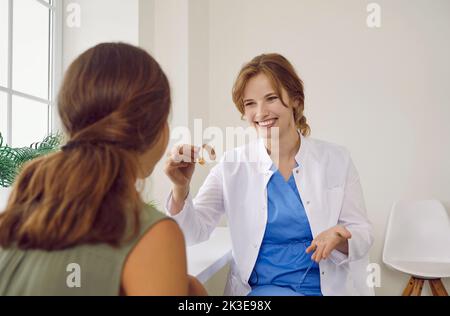 Happy, smiling audiologist gives modern hearing aid to child with hearing impairment Stock Photo