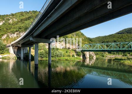 Two bridges over the river - one railway and one traffic bridge. Reflections in the water. Stock Photo