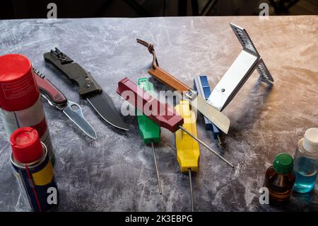 Various knives and sharpening stones. Care and repair of knives and tools. Workshop. View from above. Stock Photo