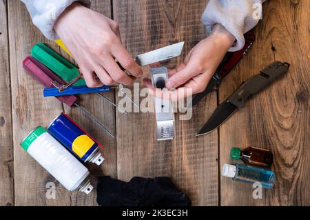 The sharpener inserts the knife into the sharpening system. Sharpening knives and tools. Knife workshop. View from above. Stock Photo