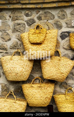 Vintage hand woven straw bags hang on the wall Stock Photo