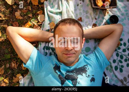 a guy talks on the phone and laughs at a picnic in the fall Stock Photo