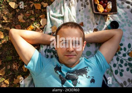 the man is lying on a blanket and laughing at a picnic in the fall Stock Photo