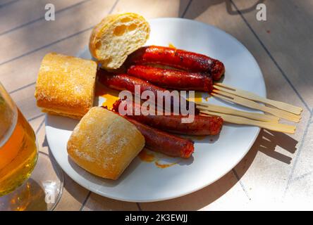 Mildly spiced grilled mini sausages chistorra. Tapa from Basque Country cuisine Stock Photo