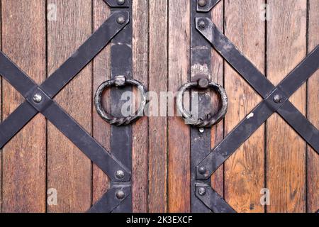 Weathered wood door with handles and iron bars Stock Photo