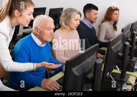 Serious business woman helping to male partner, pointing at computer monitor Stock Photo