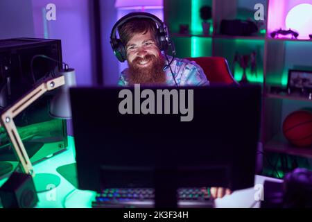Young redhead man streamer playing video game using computer at gaming room Stock Photo