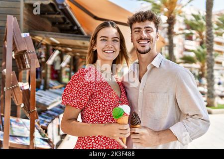 Young hispanic couple smiling happy eating ice cream standing at the city. Stock Photo