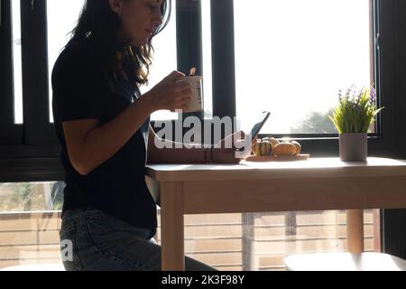 a middle-aged woman using cell phone while drinking coffee Stock Photo