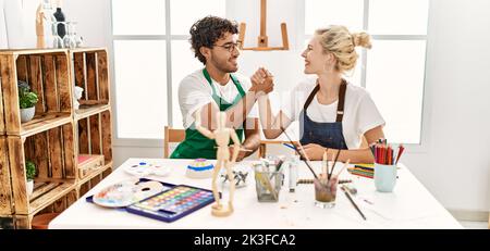 Young artist couple smiling happy shaking hands at art studio. Stock Photo